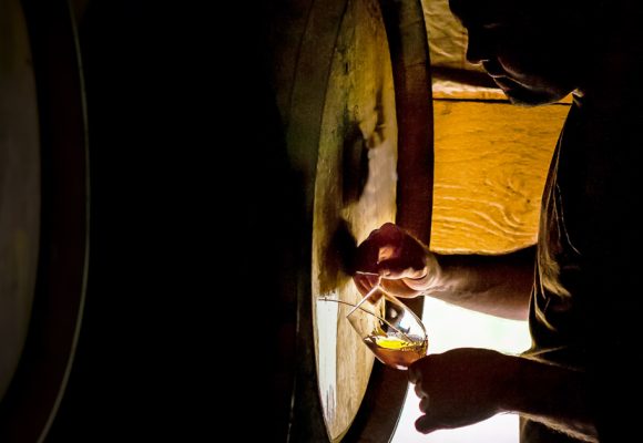 man collecting barrel aged beer from barrel