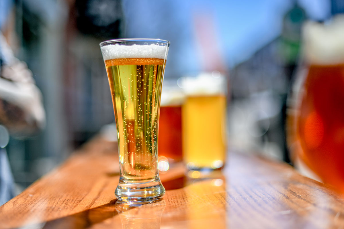 pilsner beer on sunny patio with ales in background